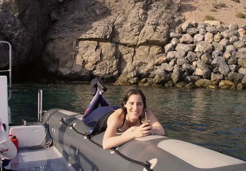 Jeune femme souriante se relaxe sur un bateau pneumatique gris