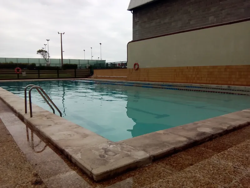 Piscine extérieure rectangulaire avec escalier d'accès et mur adjacent