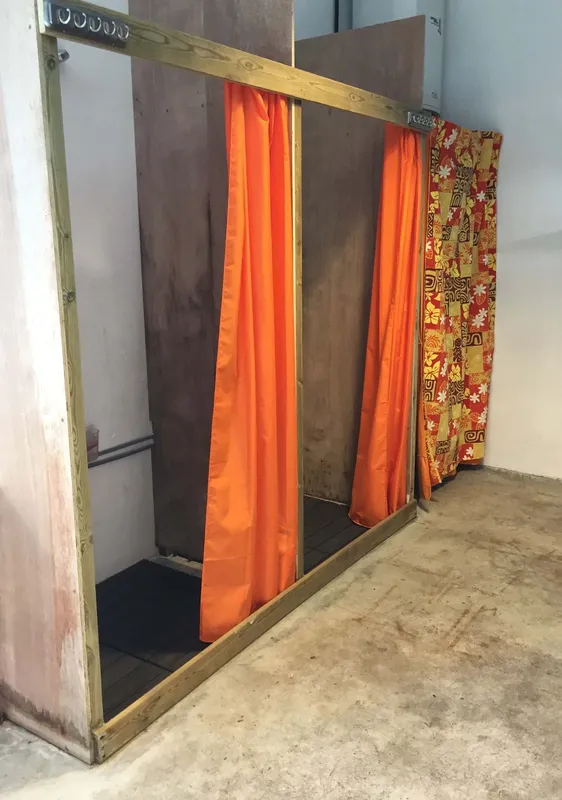 Deux cabines de douche rudimentaires avec rideaux colorés et sol carrelé