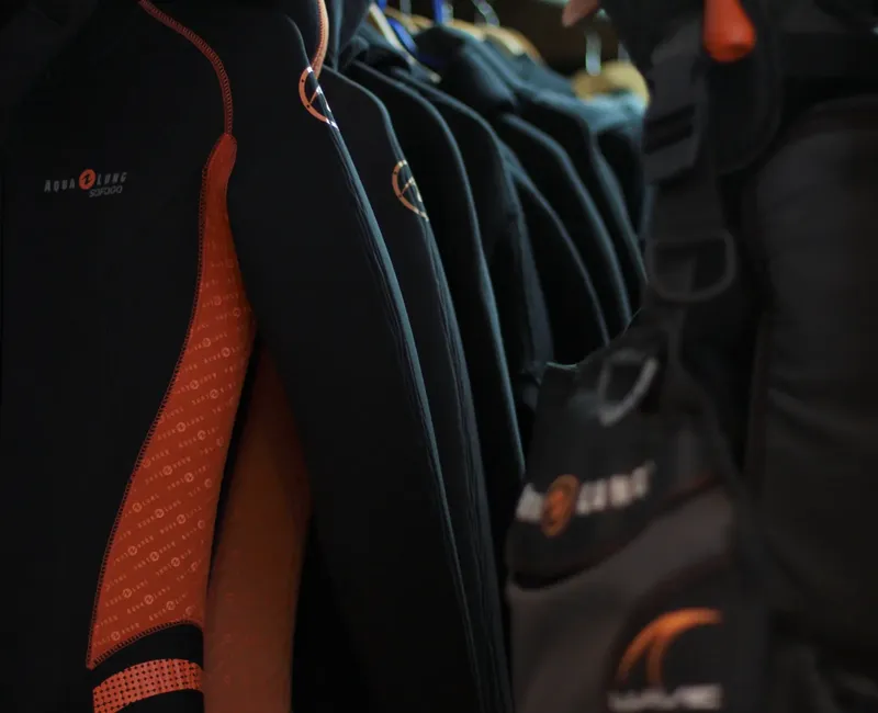 Rangée de combinaisons de plongée noires et orange prêtes à l'utilisation