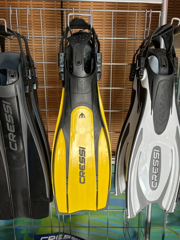 Trois paires de palmes Cressi, noires et jaunes, suspendues côte à côte