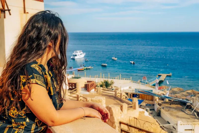 Femme regardant la mer et les bateaux depuis une terrasse ensoleillée