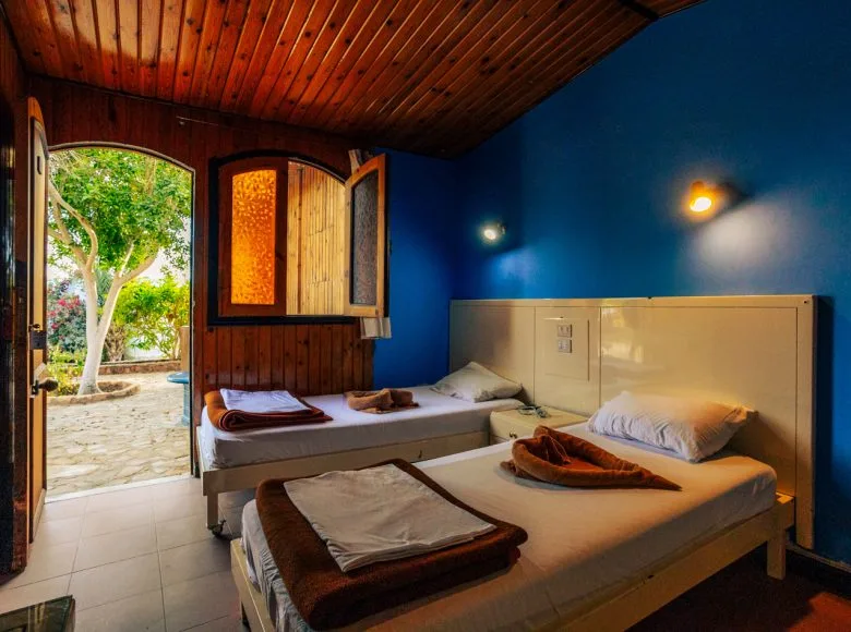 Chambre avec deux lits simples, vue sur une cour arborée ensoleillée