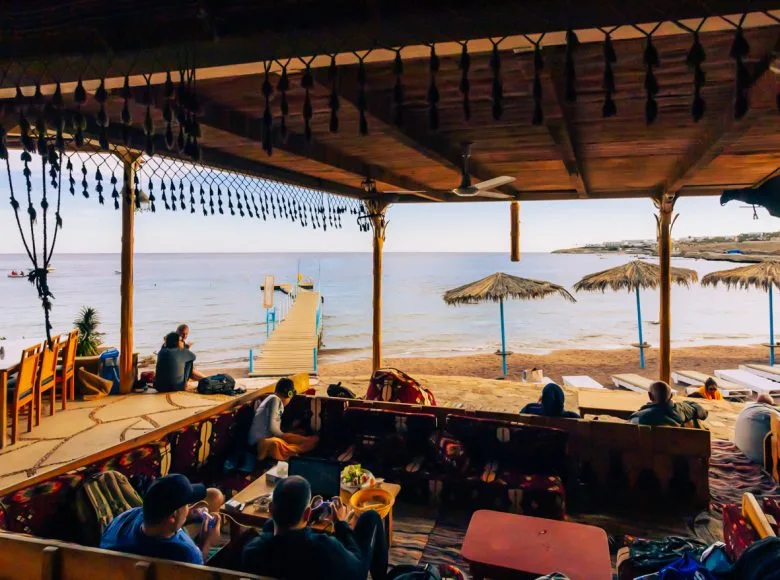 Terrasse ombragée avec vue sur la mer et des personnes assises