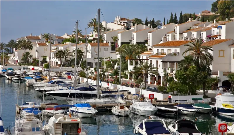 Port de plaisance ensoleillé avec bateaux à quai et bâtiments blancs