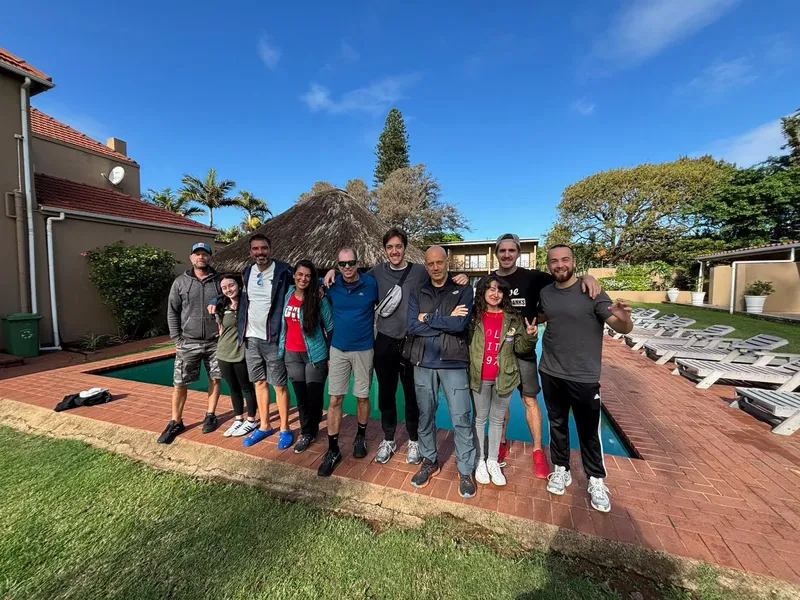 Groupe de personnes souriantes posant devant un bâtiment et une piscine