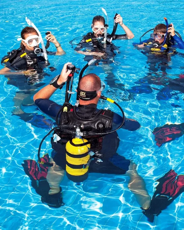 Quatre plongeurs en formation dans une piscine, équipement complet visible