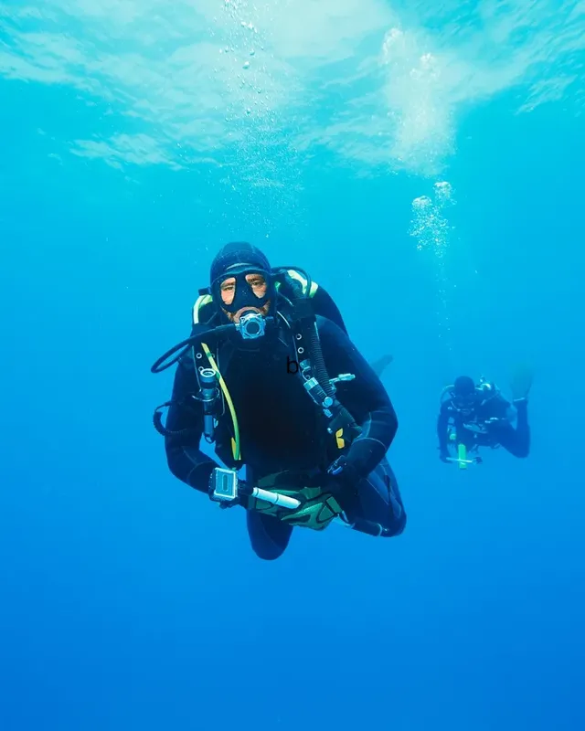 Deux plongeurs en combinaison explorent les profondeurs bleues de la mer