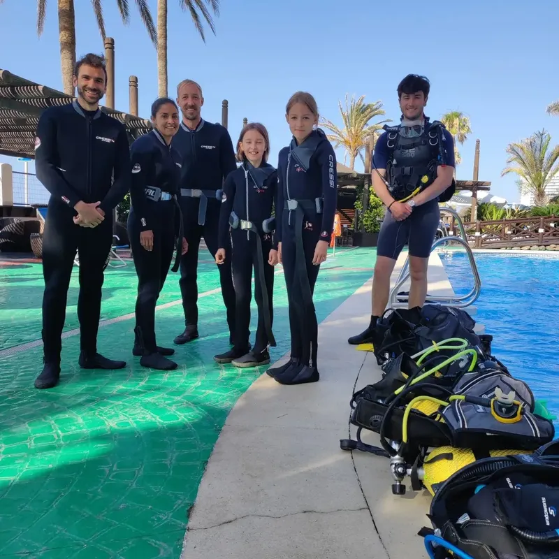 Groupe de plongeurs en combinaison près d'une piscine et du matériel