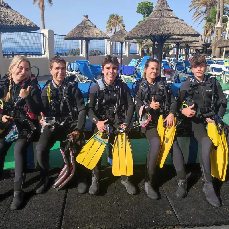 Groupe de plongeurs souriants équipés prêts pour une sortie en mer