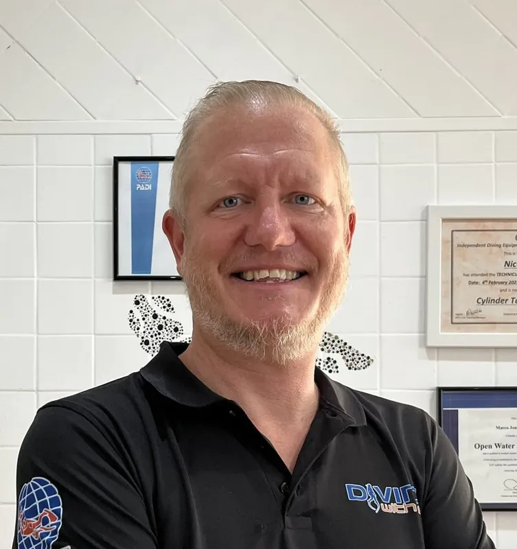 Portrait d'un homme souriant dans un intérieur clair avec des certificats