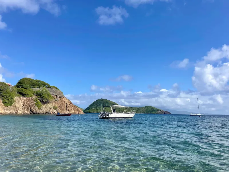 Bateau de plongée amarré dans une baie turquoise sous un ciel bleu