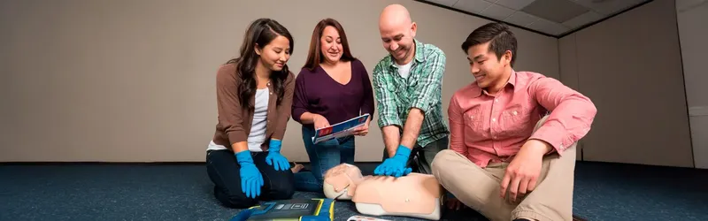 Quatre personnes suivent une formation de premiers secours avec un mannequin