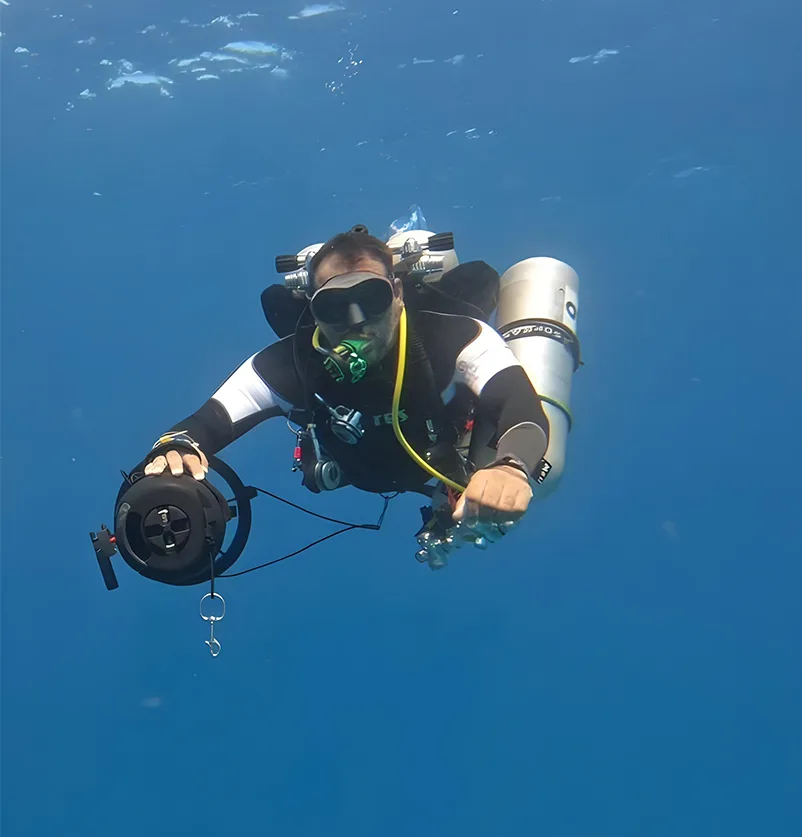 Plongeur équipé en combinaison, appareil photo, explorant les fonds marins bleus