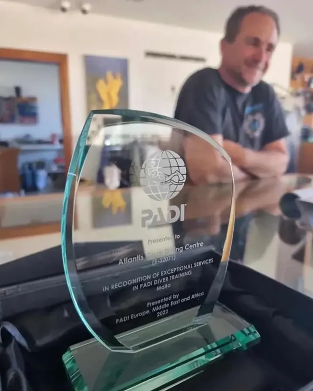 Un homme tient un trophée de verre avec le logo PADI gravé