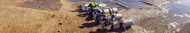 Rangée de bouteilles de plongée sur une plage de sable clair