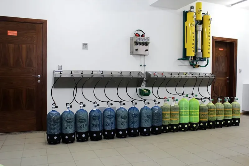 Rangée de bouteilles de plongée bleues et vertes connectées à un compresseur