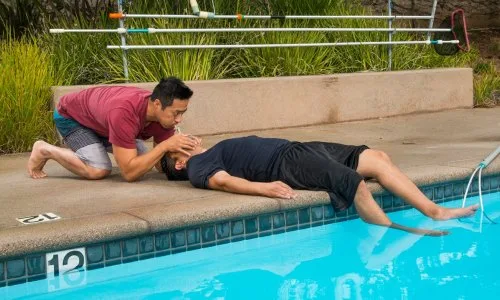 Un homme prodigue les premiers secours à un autre au bord d'une piscine