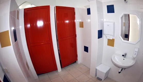 Intérieur d'une salle de bain avec lavabo, toilettes et portes rouges