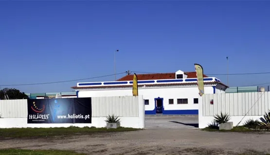 Façade d'un bâtiment blanc avec des drapeaux et une clôture verte