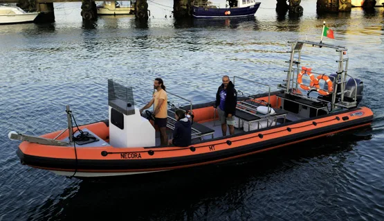 Bateau de plongée orange et noir amarré avec des personnes à bord