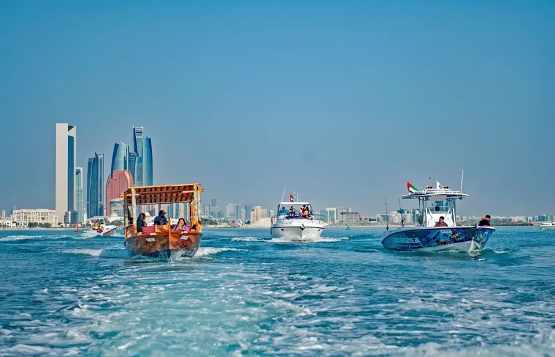 Plusieurs bateaux naviguent sur une mer calme devant une ville