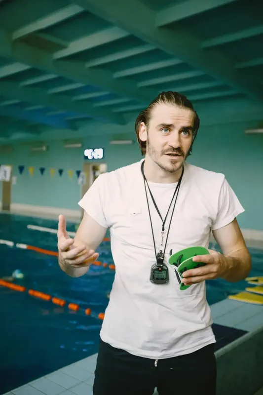 Un homme parle avec les mains devant une piscine intérieure