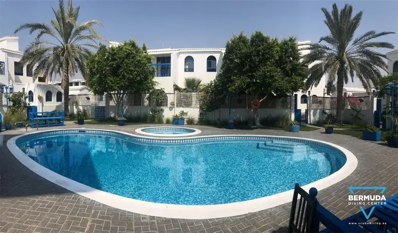 Piscine extérieure d'un centre de plongée avec bâtiments blancs et végétation