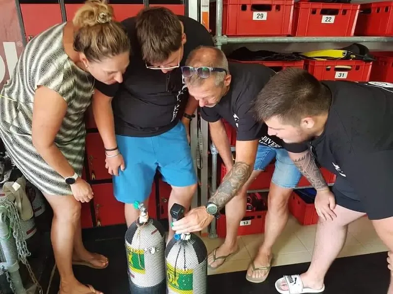 Quatre personnes examinent des bouteilles de plongée dans un local