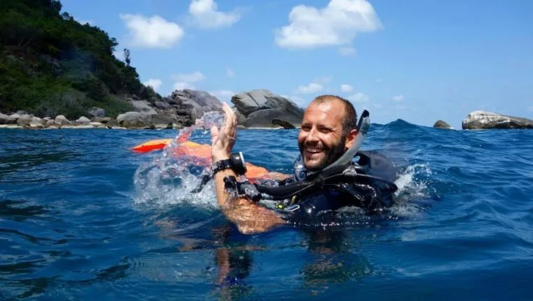 Plongeur souriant émerge de l'eau avec son équipement complet
