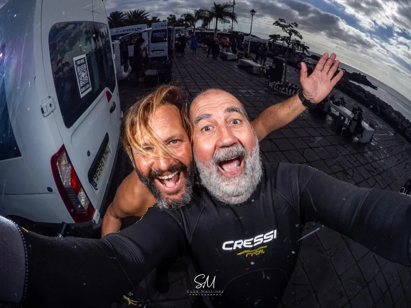 Deux hommes souriants font un selfie sur un quai ensoleillé