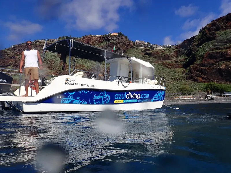 Bateau de plongée amarré près d'une côte rocheuse ensoleillée avec une personne