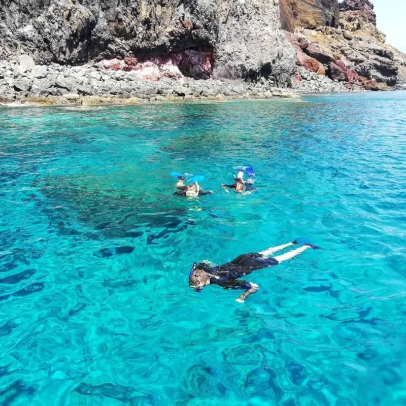 Trois personnes en snorkeling explorent une eau turquoise et claire