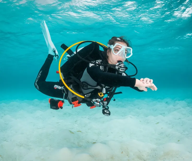 Plongeuse en combinaison noire nageant dans une eau turquoise claire