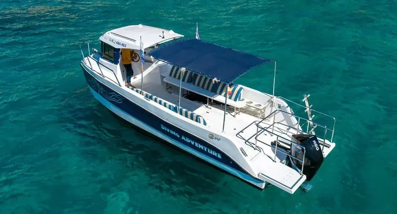Bateau de plongée blanc et bleu navigue sur une eau turquoise claire