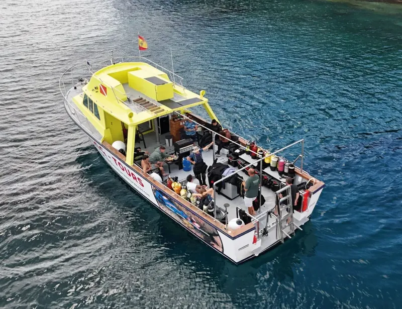 Bateau de plongée jaune avec des plongeurs et de l'équipement à bord