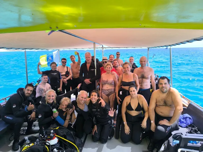 Groupe de plongeurs souriants sur un bateau en mer, équipement visible