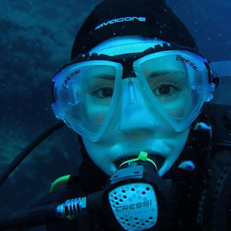 Plongeuse souriante avec masque et détendeur sous l'eau bleue