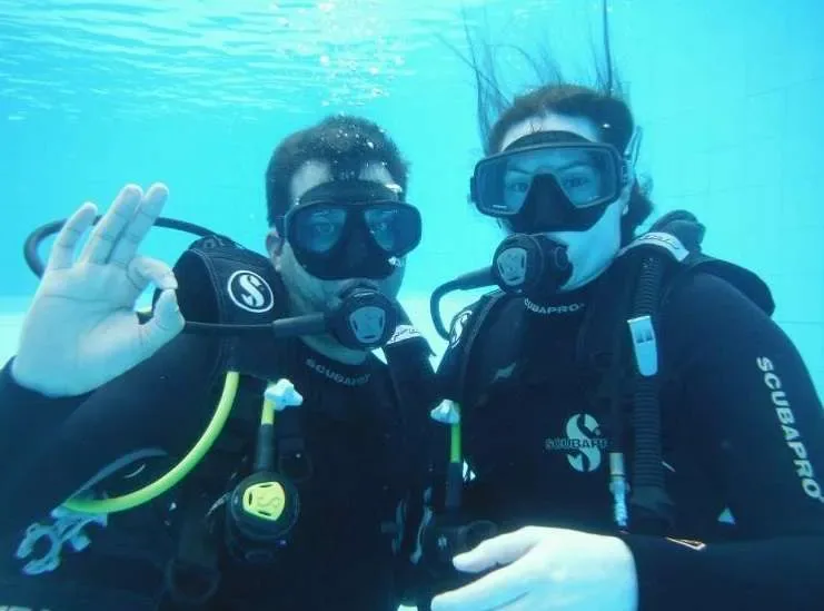 Deux plongeurs souriants font un signe de paix sous l'eau