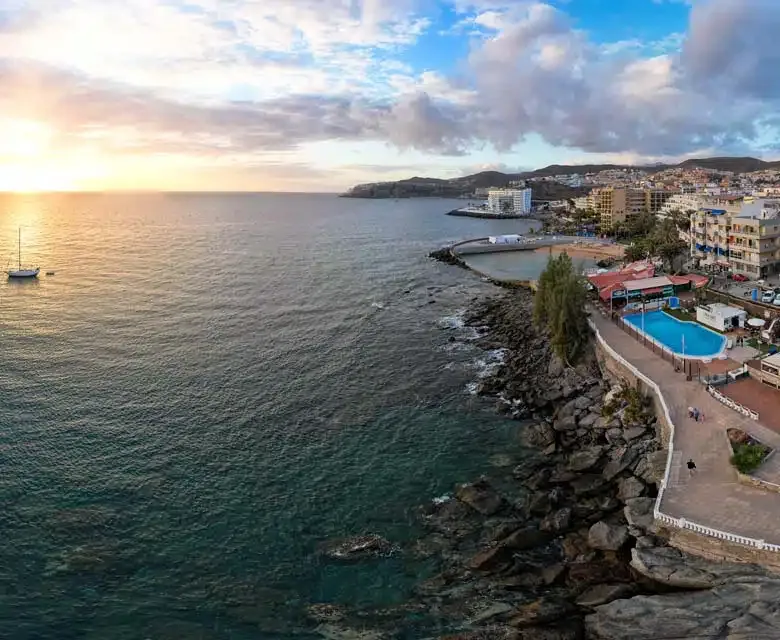Vue aérienne d'une côte rocheuse avec un bateau en mer et une piscine