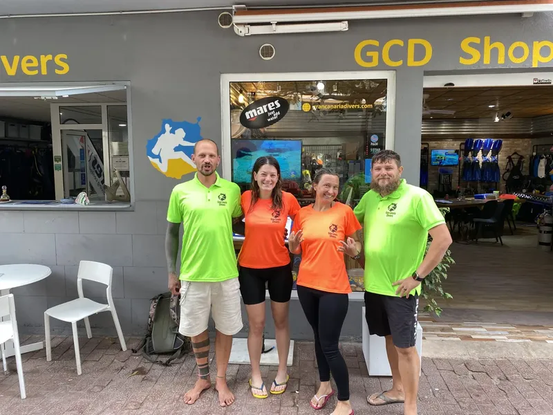 Quatre personnes souriantes devant la boutique d'un centre de plongée