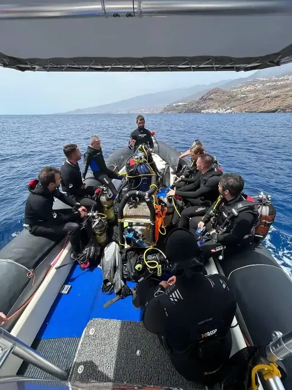 Groupe de plongeurs en équipement complet à bord d'un bateau pneumatique bleu