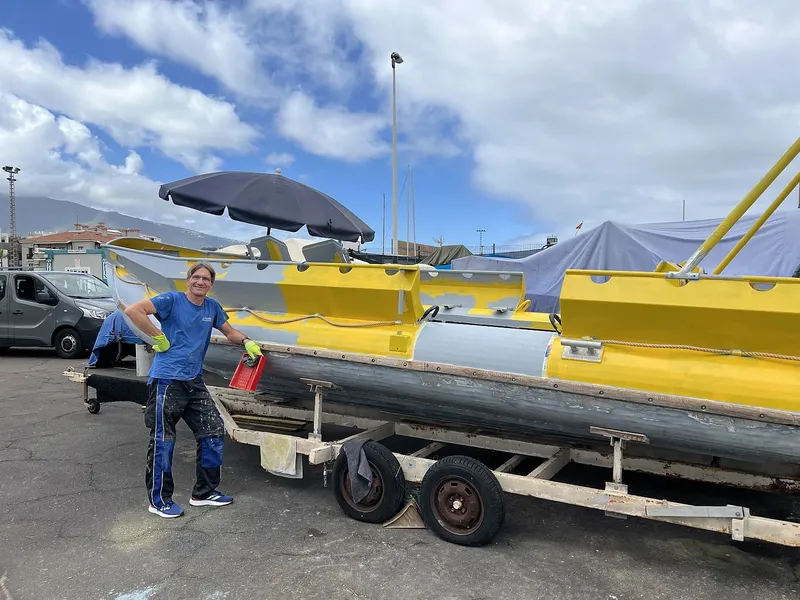 Homme debout près d'un bateau jaune sur une remorque