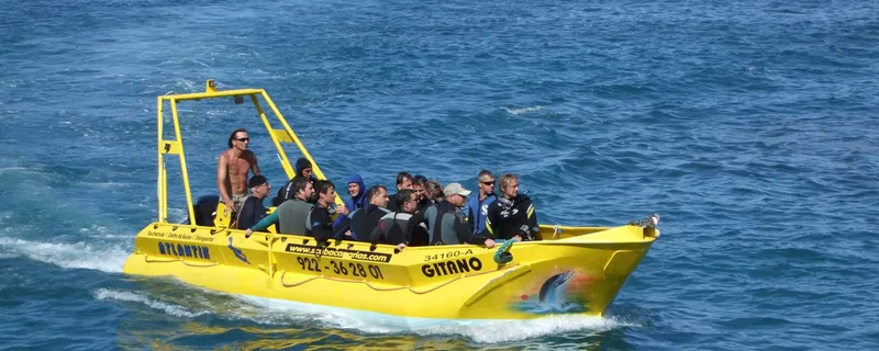 Bateau jaune rempli de plongeurs naviguant sur une mer bleue calme