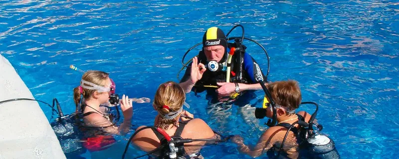Trois plongeurs en formation avec un instructeur dans une piscine