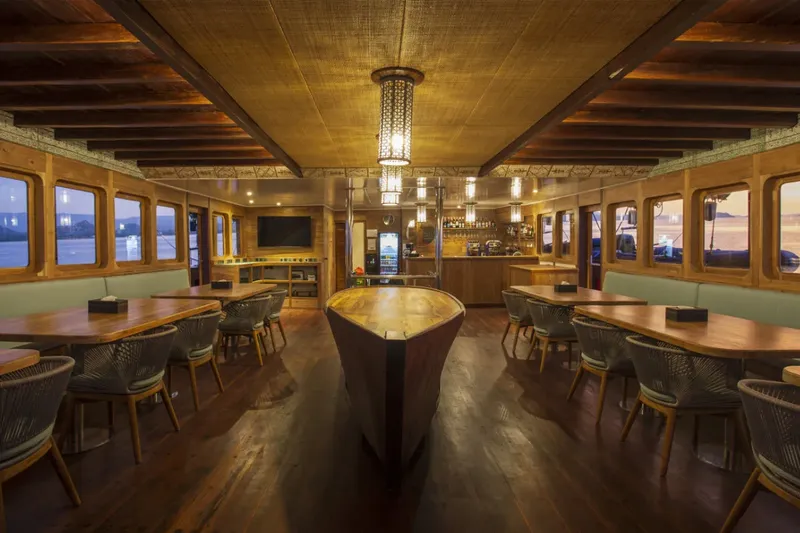 Intérieur d'un bateau de plongée avec tables, chaises et éclairage chaleureux