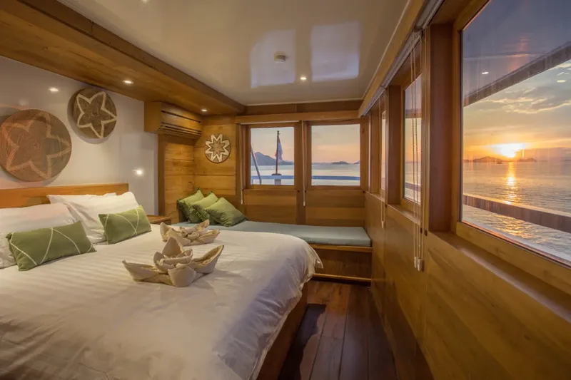 Intérieur de bateau avec lit, vue sur mer et coucher de soleil