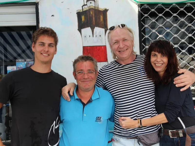 Quatre personnes souriantes posent devant un mur peint et une devanture