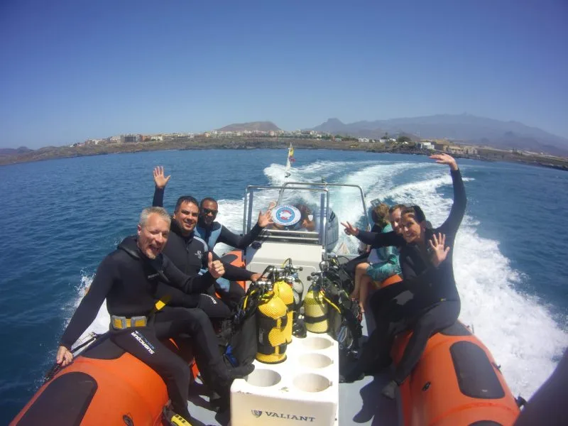 Groupe de plongeurs souriants sur un bateau semi-rigide en mer