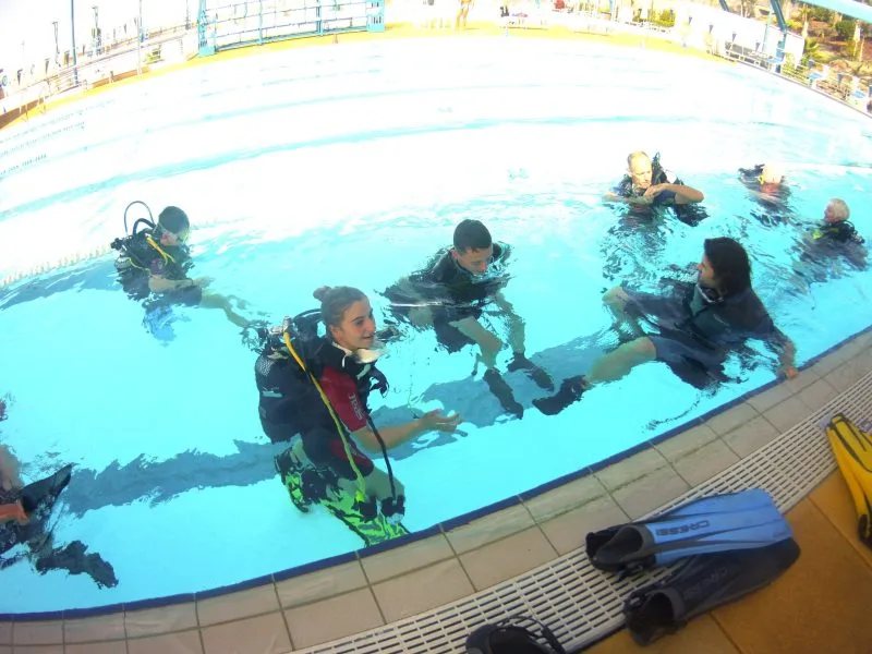 Plusieurs plongeurs en formation dans une piscine, équipement complet visible